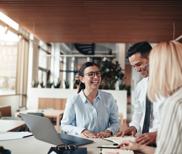 Businesspeople laughing while working at an office table